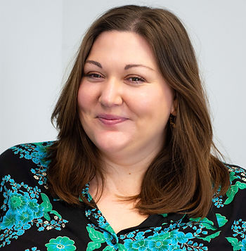 A woman with long hair and a floral print shirt smiles 