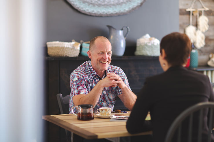 Vision Coaching CEO Dave Veale smiles in conversation as he sits across the table from a woman.