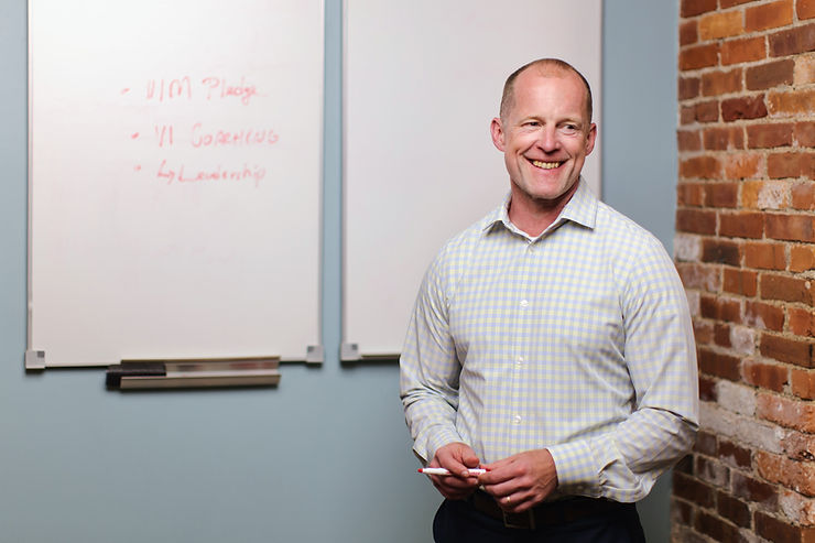 Vision Coaching CEO Dave Veale stands at a white board, smiling. The words 1 Million Pledge appear on the board.