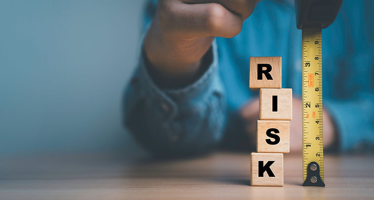 Man uses a measuring tape to size up wooden blocks that spell the word risk.